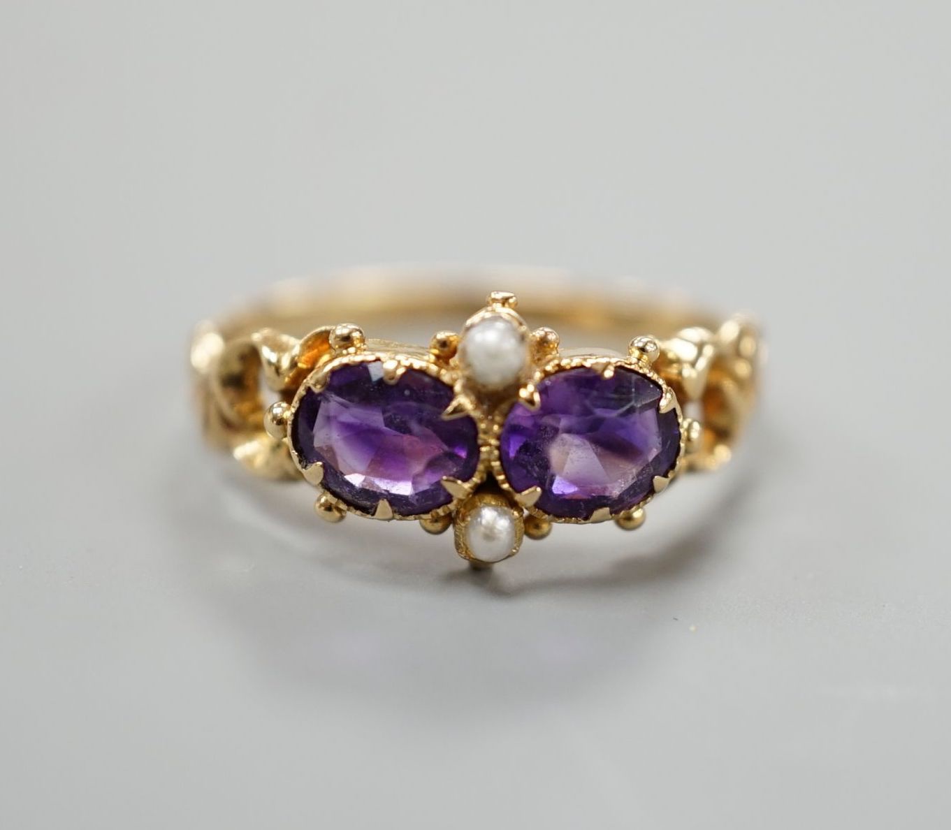 A late Victorian yellow metal, two stone amethyst and two stone seed pearl set cluster ring, size L, gross weight 2.1 grams.